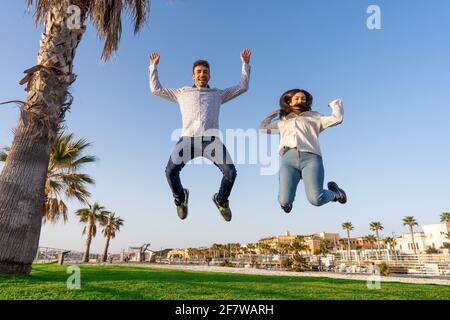 Glückliche Menschen freuen sich über den Erfolg des Lebens, das in der Luft mit offenen Armen auf die Kamera blickt. Zwei junge Studenten in der Stadt Natur genießen Freiheit SM Stockfoto