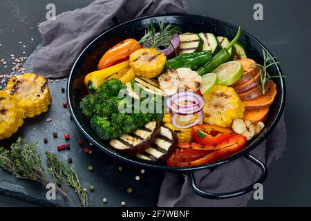 Gegrilltes Gemüse in gusseiserner Pfanne auf schwarzem Hintergrund. Grillmenü. Stockfoto