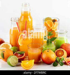 Rohe frische Zitrusfrüchte und Früchte in Gläsern und Flaschen Auf weißem Hintergrund Stockfoto
