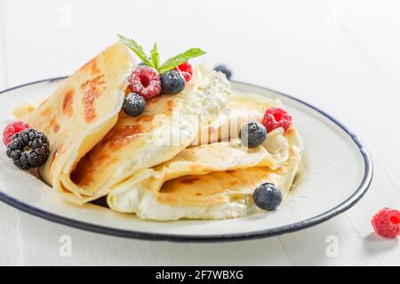 Süße und leckere Pfannkuchen mit Quark und Beeren. Pfannkuchen zum Frühstück. Stockfoto