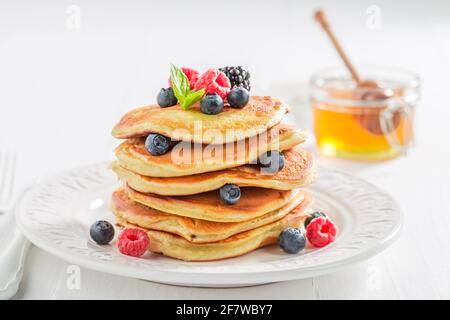 Süße und hausgemachte amerikanische Pfannkuchen mit Beeren und Honig. Pfannkuchen zum Frühstück. Stockfoto