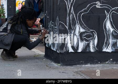 Straßenkünstlerin Folie arbeitet an einem Gemälde im Northern Quarter of Manchester UK. Wenn die Winde nicht dienen, bringt sie zu den Rudern. Stockfoto