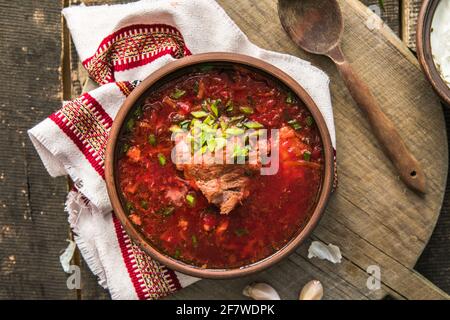 Borscht – traditionelle ukrainische Gerichte. Gemüsesuppe aus Rüben, Kartoffeln, Getreide und gekochtem Fleisch und Scheiben Roggenbrot in einer Keramikschale o Stockfoto