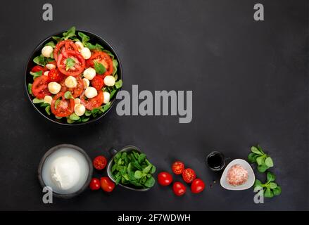 Köstlicher italienischer Caprese-Salat mit geschnittenen Tomaten und Mozzarela auf dunklem Hintergrund. Gesundes Lebensmittelkonzept. Draufsicht, Kopierbereich Stockfoto