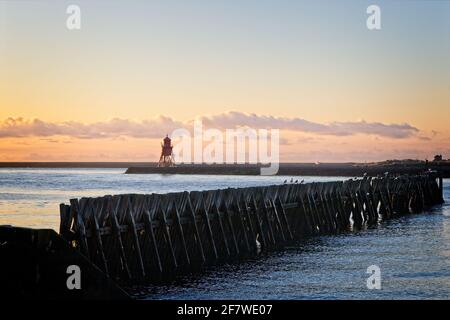 In der Mündung des Flusses Tyne stehen alte Holzkehlchen. Aufgenommen vom North Shields Fish Quay Beach mit Blick auf den Groyne Lighthouse. Stockfoto