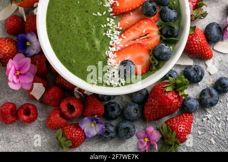 Matcha Grüner Tee Frühstück Superfoods Smoothies Schüssel mit Erdbeeren, Heidelbeeren, Kokosflocken obendrauf, Draufsicht, flach legen Stockfoto