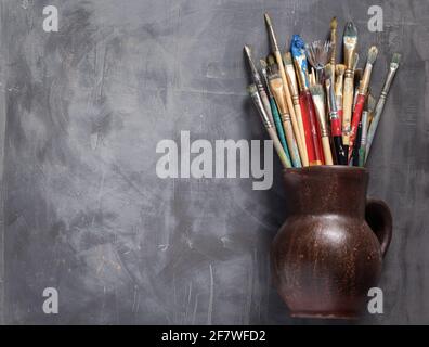 Pinsel in Tonkrug oder Topf auf abstrakten Tisch Hintergrund Textur malen. Kunstmaler Konzept Stockfoto