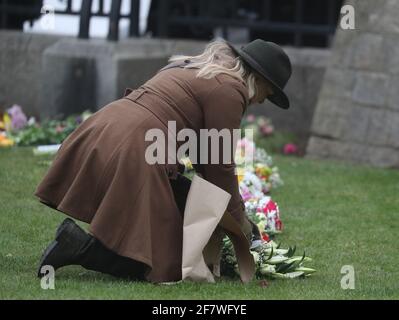 Eine Frau hinterlässt Blumen vor Windsor Castle, in der Nähe von Burkshire, nachdem am Freitag, dem 9. April, der Tod des Herzogs von Edinburgh im Alter von 99 Jahren angekündigt wurde. Bilddatum: Samstag, 10. April 2021. Stockfoto