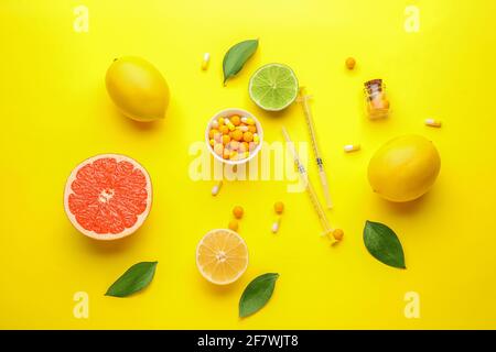 Spritzen mit Vitamin C, Pillen und Zitrusfrüchten auf farbigem Hintergrund Stockfoto