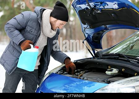 Mann mit Ölbehälter in der Nähe des Autos am Wintertag Stockfoto