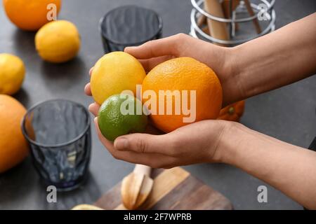 Frau mit frischen Zitrusfrüchten auf dunklem Hintergrund Stockfoto