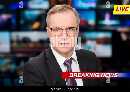Ein Anchorman, der im Fernsehstudio aktuelle Nachrichten berichtet. Hintergrund mehrerer Bildschirme des Kontrollraums. Journalismus-Konzept Stockfoto