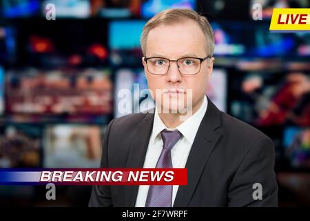 Ein Anchorman, der im Fernsehstudio aktuelle Nachrichten berichtet. Hintergrund mehrerer Bildschirme des Kontrollraums. Journalismus-Konzept Stockfoto