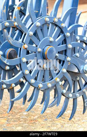 Eine gezahnte Metallegge von blauer Farbe auf der Anhängevorrichtung eines Traktors für die landwirtschaftliche Verarbeitung von Feldern. Vertikales Bild, Kopierbereich. Stockfoto