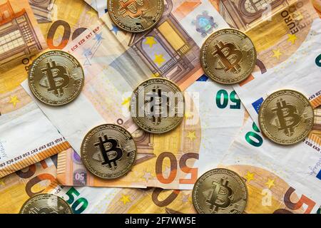 Overhead-Ansicht einiger Bitcoins auf einem Hintergrund von 50-Euro-Scheinen. Bitcoin als neues Geld, Börse von Kryptowährungen und dezentrale Finanzen con Stockfoto