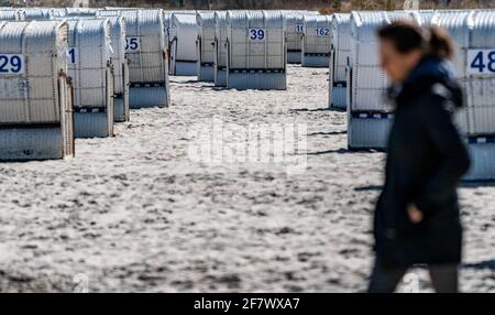 Timmendorfer Strand, Deutschland. April 2021. Eine Frau geht in strahlendem Sonnenschein zwischen den ersten Strandliegen, die in diesem Jahr aufgestellt wurden, am Timmendorfer Strand entlang. Quelle: Axel Heimken/dpa/Alamy Live News Stockfoto