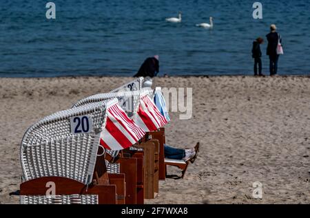 Timmendorfer Strand, Deutschland. April 2021. Bei strahlendem Sonnenschein laufen die Menschen am Timmendorfer Strand entlang hinter den ersten Strandliegen, die dieses Jahr aufgestellt wurden. Quelle: Axel Heimken/dpa/Alamy Live News Stockfoto