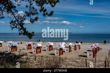 Timmendorfer Strand, Deutschland. April 2021. Bei strahlendem Sonnenschein laufen die Menschen am Timmendorfer Strand entlang hinter den ersten Strandliegen, die dieses Jahr aufgestellt wurden. Quelle: Axel Heimken/dpa/Alamy Live News Stockfoto