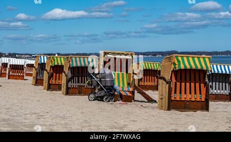 Timmendorfer Strand, Deutschland. April 2021. Eine Frau beugt sich im strahlenden Sonnenschein am Timmendorfer Strand zwischen den ersten Strandliegen, die dieses Jahr aufgestellt wurden. Quelle: Axel Heimken/dpa/Alamy Live News Stockfoto