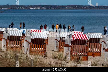 Timmendorfer Strand, Deutschland. April 2021. Bei strahlendem Sonnenschein laufen die Menschen am Timmendorfer Strand entlang hinter den ersten Strandliegen, die dieses Jahr aufgestellt wurden. Quelle: Axel Heimken/dpa/Alamy Live News Stockfoto