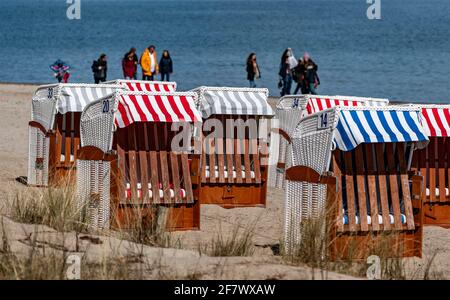 Timmendorfer Strand, Deutschland. April 2021. Bei strahlendem Sonnenschein laufen die Menschen am Timmendorfer Strand entlang hinter den ersten Strandliegen, die dieses Jahr aufgestellt wurden. Quelle: Axel Heimken/dpa/Alamy Live News Stockfoto