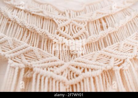 Handgemachtes Makramenmuster ein Fragment einer Wandtafel in Der Boho-Stil aus beigefarbenen Baumwollfäden mit natürlicher Farbe Mit der Technik für zu Hause und Weddin Stockfoto