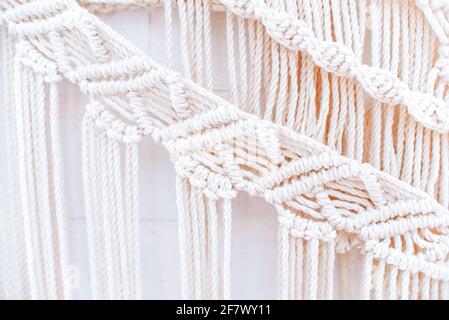 Handgemachtes Makramenmuster ein Fragment einer Wandtafel in Der Boho-Stil aus beigefarbenen Baumwollfäden mit natürlicher Farbe Mit der Technik für zu Hause und Weddin Stockfoto