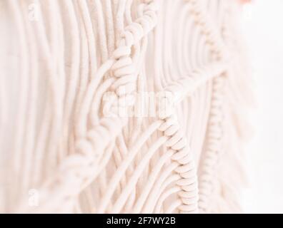 Handgemachtes Makramenmuster ein Fragment einer Wandtafel in Der Boho-Stil aus beigefarbenen Baumwollfäden mit natürlicher Farbe Mit der Technik für zu Hause und Weddin Stockfoto