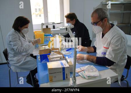 Krankenschwestern in der Apotheke bereiten unter Anleitung eines Arztes Spritzen mit Dosen von pfizer-biontech-Impfstoff oder astrazeneca vor. Stockfoto