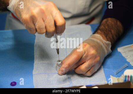 Krankenschwestern in der Apotheke bereiten unter Anleitung eines Arztes Spritzen mit Dosen von pfizer-biontech-Impfstoff oder astrazeneca vor. Stockfoto