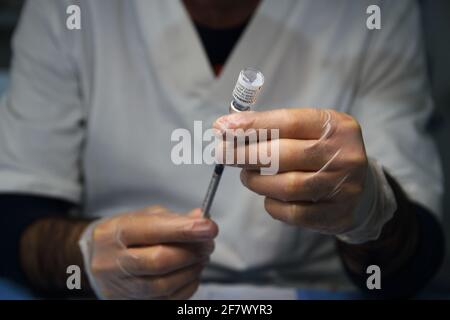 Krankenschwestern in der Apotheke bereiten unter Anleitung eines Arztes Spritzen mit Dosen von pfizer-biontech-Impfstoff oder astrazeneca vor. Stockfoto