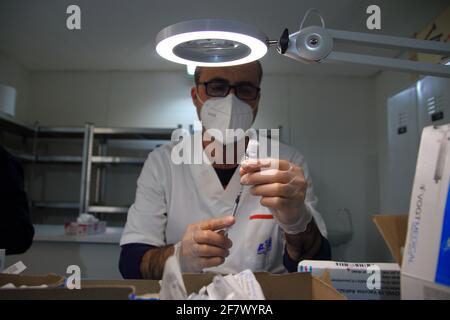 Krankenschwestern in der Apotheke bereiten unter Anleitung eines Arztes Spritzen mit Dosen von pfizer-biontech-Impfstoff oder astrazeneca vor. Stockfoto