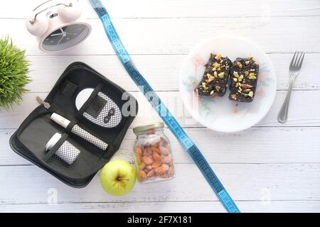 Messgeräte für Diabetiker, Insulin und Browni auf Holztisch Stockfoto