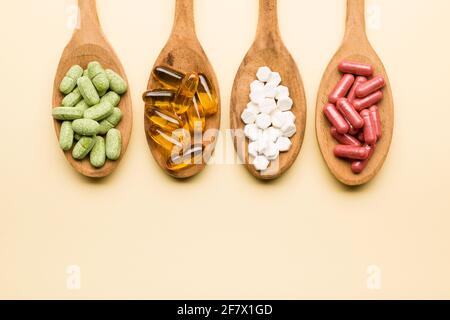 Mischung von Supplement Pillen auf Holzlöffel auf gelbem Hintergrund Stockfoto