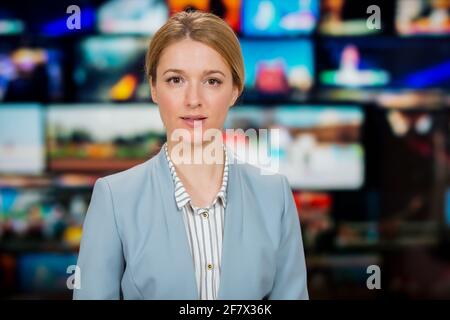 Eine Anchorfrau, die im Fernsehstudio aktuelle Nachrichten berichtet. Hintergrund mehrerer Bildschirme des Kontrollraums. Journalismus-Konzept Stockfoto