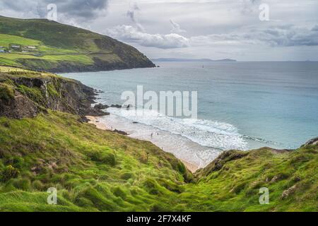 Menschen, die in türkisfarbenen See und in der Nähe von Coumeenoole Beach zwischen Klippen auf der Halbinsel Dingle, Wild Atlantic Way, Kerry, Irland, schwimmen Stockfoto