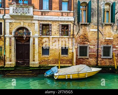 Seitenansicht eines gelben Bootes, das vor der Anlegestelle liegt Ein wunderschönes altes venezianisches Backsteinhaus aus roten Ziegeln Stockfoto