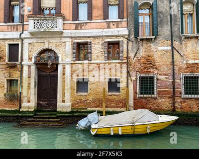 Seitenansicht eines gelben Bootes, das vor der Anlegestelle liegt Ein venitianisches Haus Stockfoto