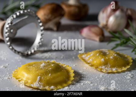 Mit Pilzen gefüllte Ravioli und rohe Zutaten. Stockfoto