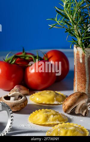 Mit Pilzen gefüllte Ravioli und rohe Zutaten. Stockfoto