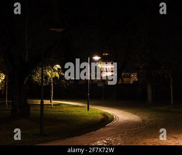 Nachtfoto einer Gasse in der mittelalterlichen Zitadelle von Marosvasarhely. Im Hintergrund sieht man die Türme einer orthodoxen Kirche. Stockfoto