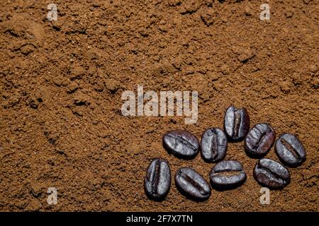 Gemahlener schwarzer Kaffee-Hintergrund mit ein paar ganzen schwarzen Kaffee Bohnen Stockfoto
