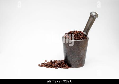 Schwarzer Kaffee in Bohnen in einem Metallmörtel auf einem Weißer Hintergrund Stockfoto