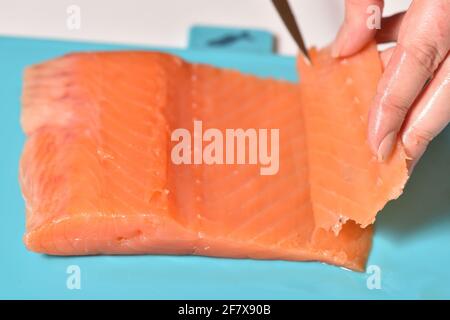 Der Küchenchef schneidet roten Fisch in dünne Scheiben Stockfoto