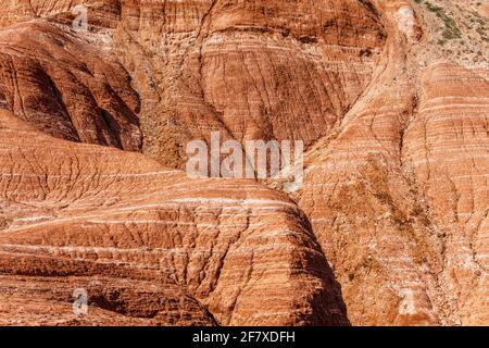 Rot-orange geschichtete Berge, durchsetzt mit hellen Schichten. Hintergrund. Stockfoto