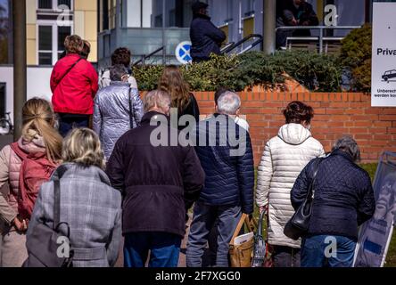 10. April 2021, Mecklenburg-Vorpommern, Wismar: Menschen stehen in einer Schlange vor dem Impfzentrum in Wismar und warten auf ihren Impftermin. Die Landesregierung Mecklenburg-Vorpommern erhöht den Druck auf Landkreise und unabhängige Städte, den Impfstoff von AstraZeneca unverzüglich einzusetzen. Foto: Jens Büttner/dpa-Zentralbild/dpa Stockfoto