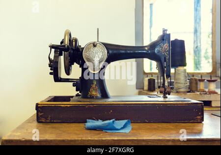 Komposition mit einer alten Nähmaschine mit Fäden und einem Stoffstück Stockfoto