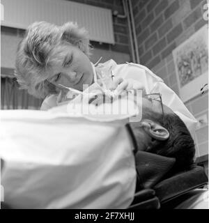 Ein Zahnarzt der Zentralkrankheit (CZB) in der Marine Barracks Willemsoord (MKWD) in Den Helder untersucht die Zähne eines Patienten (Juli 1989). Stockfoto