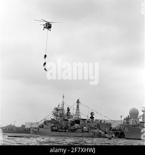 Fleet Days in Den Helder im Juli1989. Im vorderen Stockwerk links der portugiesische Fregatte-NRP-Kommandant Roberto Ivens (F 482, 1968) und rechts der Bug des amerikanischen Coontz-Klasse-Zerstörers USS Mahan (42, 1960). In der Luft der Westland SH-14D Navy Lynx Hubschrauber mit Registrierung 278 (1980-ca. 2012) des Marine Air Shipping Service (MLD) mit fünf Personen auf der Lier unten. Stockfoto