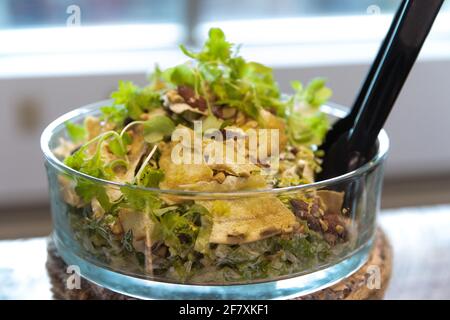 Salat in einer runden Glasschüssel mit Küchenzange Servieren Stockfoto